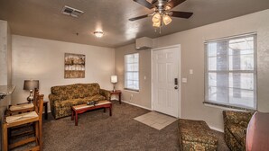 A living room with a ceiling fan, a sofa, a coffee table, and a door. - Spacious 2 Bed - Floor 1 - Reserved Parking (Oklahoma City)
