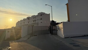 A gated entrance to a residential building complex with a clear sky and the sun setting in the background. - DEPARTAMENTO RESIDENCIAL PRIVADO ALBERCA (Puerto Vallarta)
