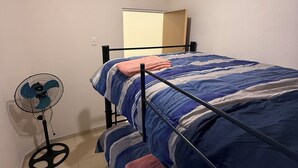 A bedroom with a bed, a standing fan, and a mirror on the wall. - DEPARTAMENTO RESIDENCIAL PRIVADO ALBERCA (Puerto Vallarta)