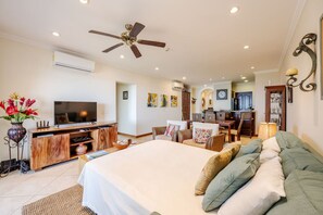 A spacious bedroom with a large bed, a TV, a wooden cabinet, and a dining area with chairs and a table. - Playa Flamingo Ocean View Retreat | Pool | Balcony (Flamingo)