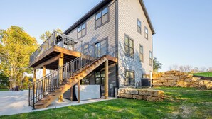 A two-story house with a wooden deck and a staircase leading to a balcony. - New construction, Hot tub, Game room, Extra-large patio, Firepit, covered porch (Galena)