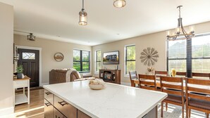 A modern kitchen with a large island, wooden cabinetry, and pendant lighting. - New construction, Hot tub, Game room, Extra-large patio, Firepit, covered porch (Galena)
