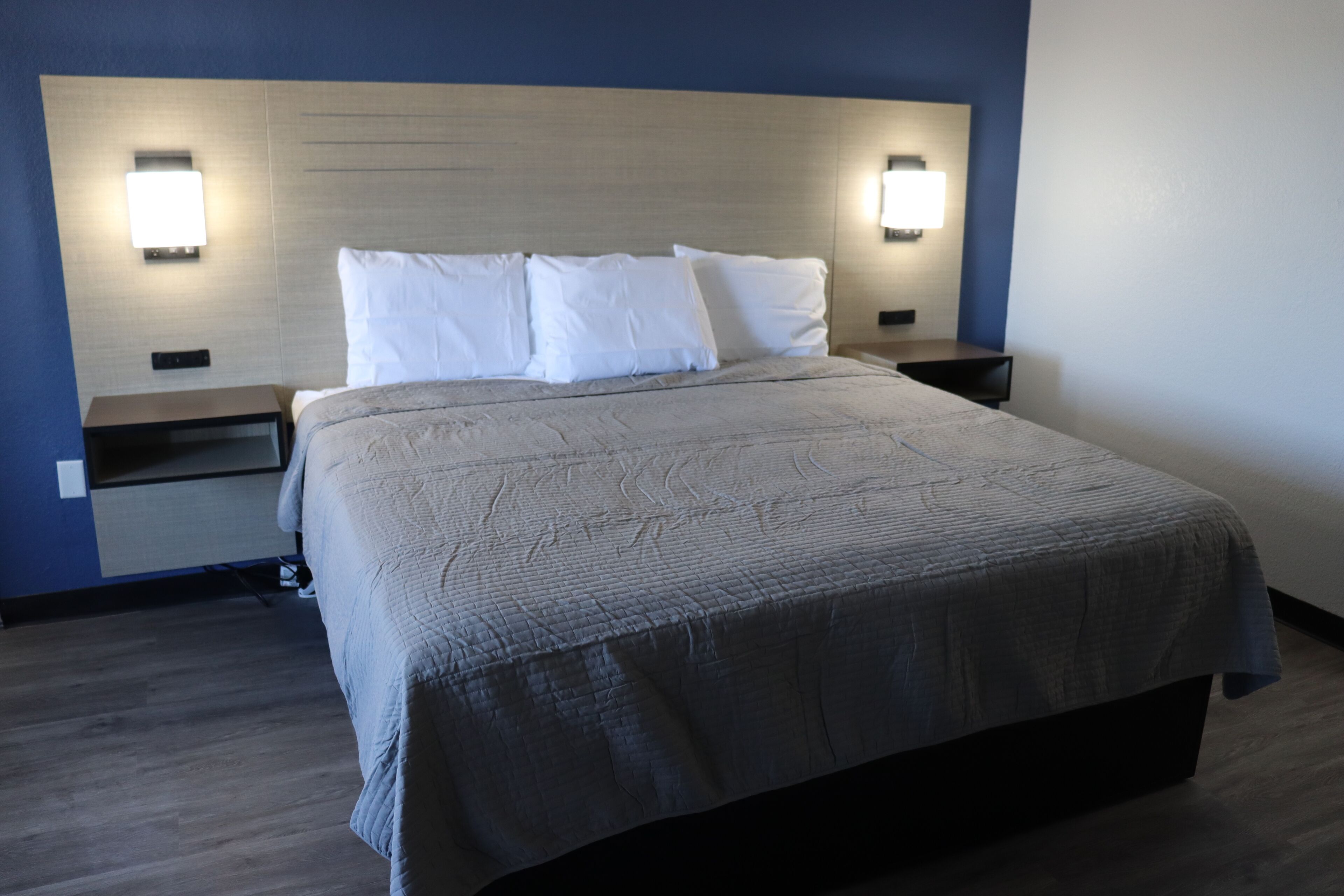 Una habitación de hotel con una cama grande, dos mesitas de noche y lámparas de pared.