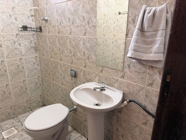 A bathroom with a toilet, sink, and tiled walls.
