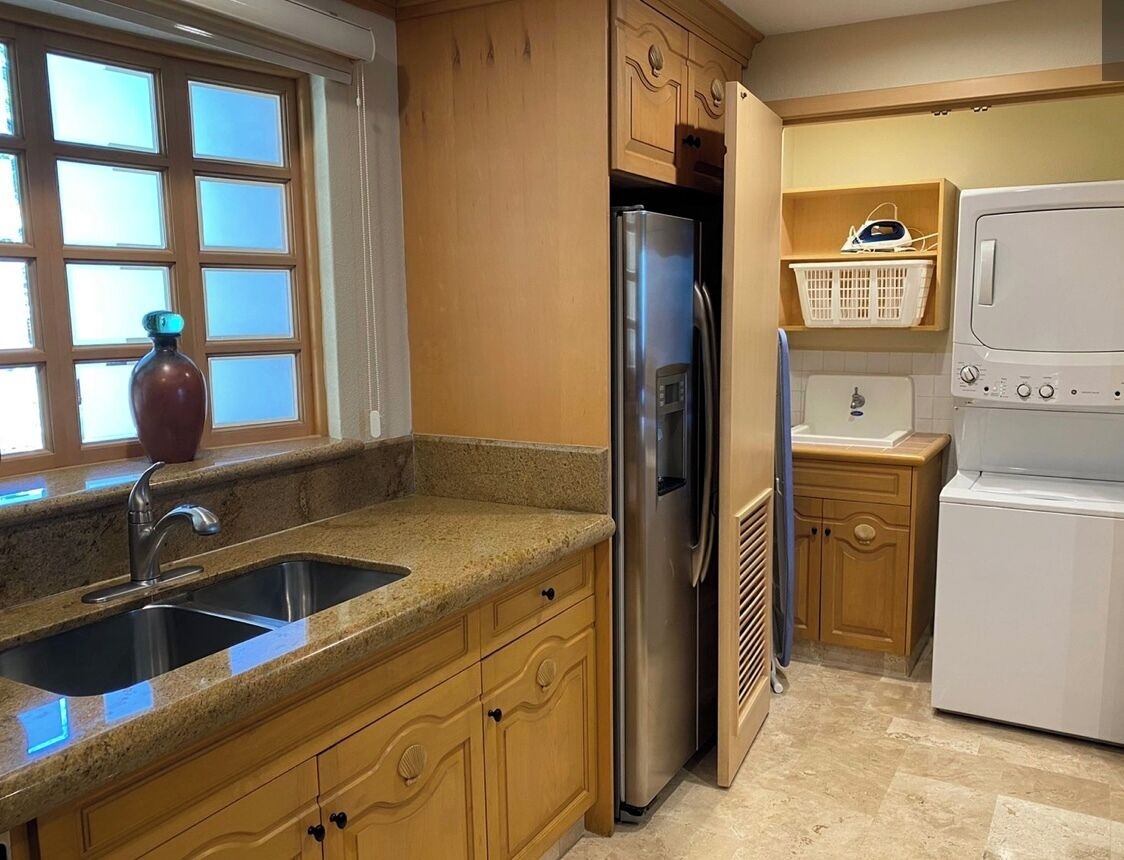 A kitchen with granite countertops, a stainless steel refrigerator, a built-in oven, and wooden cabinets.