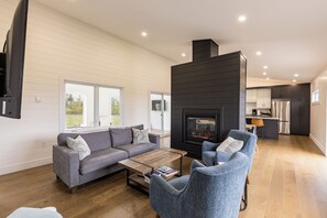 Una sala moderna con chimenea, un sofá, una mesa de centro y un comedor.