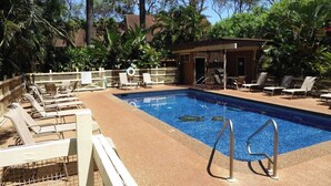 Une piscine avec des chaises longues et un petit bâtiment en arrière-plan.