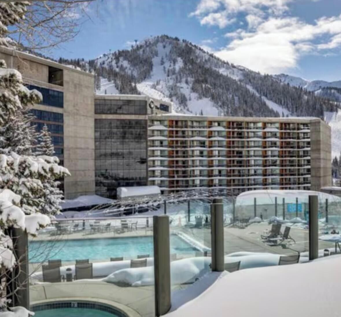 A hotel with a pool area and a mountain backdrop.