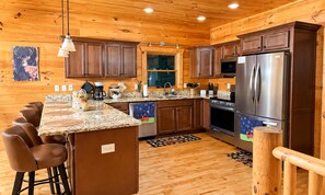 A kitchen with wooden cabinets, a stainless steel refrigerator, and a granite countertop. - Dreamy Mountain Escape, Hot Tub, Stunning mountain Views & outdoor Fireplace (Morganton)