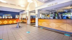 Un hall d’hôtel comprenant un comptoir d’enregistrement, un espace dédié aux conférences et un sol carrelé.