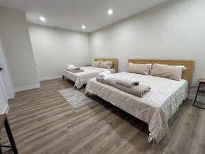 A bedroom with two beds, a wooden floor, and a small bedside table. - Brand New, Spacious 9 bedroom, 9 1/2 bath Waterfront house in Lakeside Estates (LaFollette)