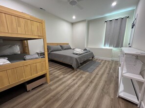 Une chambre avec un lit superposé, un lit simple, un bureau et une fenêtre avec des rideaux.