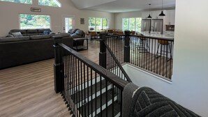 Un vaste espace de vie doté d’un haut plafond, d’un escalier et d’un coin cuisine.
