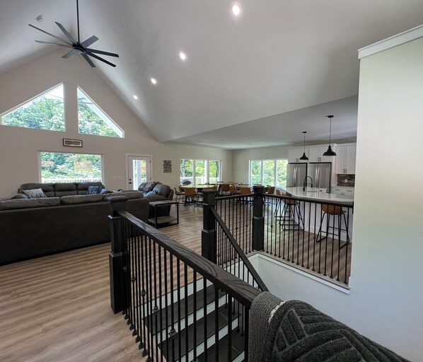 A spacious living area with a high ceiling, a staircase, and a kitchen area. - Brand New, Spacious 9 bedroom, 9 1/2 bath Waterfront house in Lakeside Estates (LaFollette)
