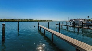 Une jetée en bois s’étendant sur une étendue d’eau calme, sous un ciel dégagé.