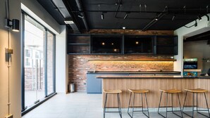 Een moderne keuken met een bakstenen muur, een houten bar en barstoelen.
