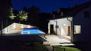 Et moderne hus med en swimmingpool, en overdækket terrasse og en trappe til indgangen.