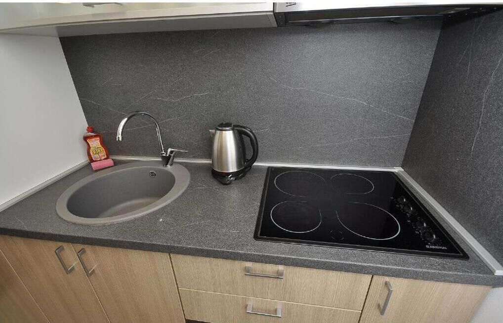 A kitchen with a sink, faucet, kettle, and induction cooktop.