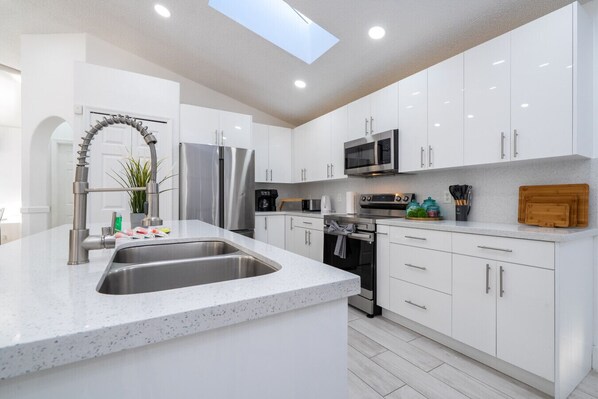 A modern kitchen with white cabinetry, stainless steel appliances, and a granite countertop. - Resort-Style Home Near Disney | Pool | Game Room (Kissimmee)