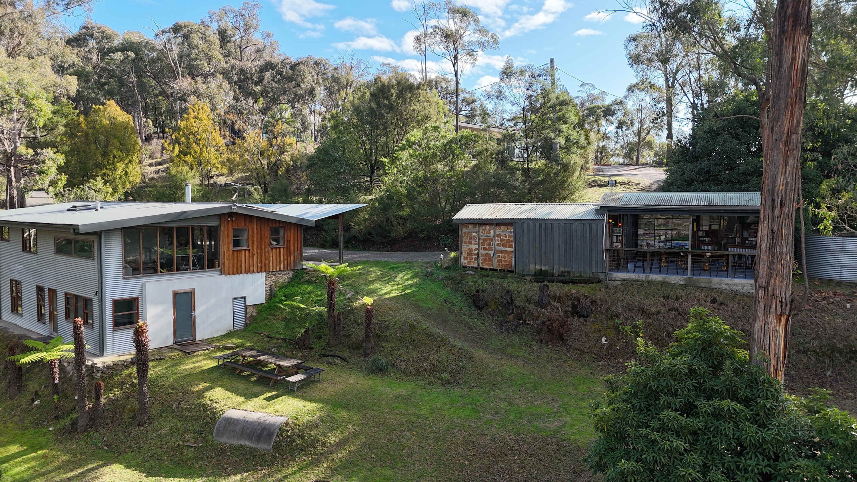 Una casa moderna con una amplia terraza, rodeada de exuberante follaje y árboles.