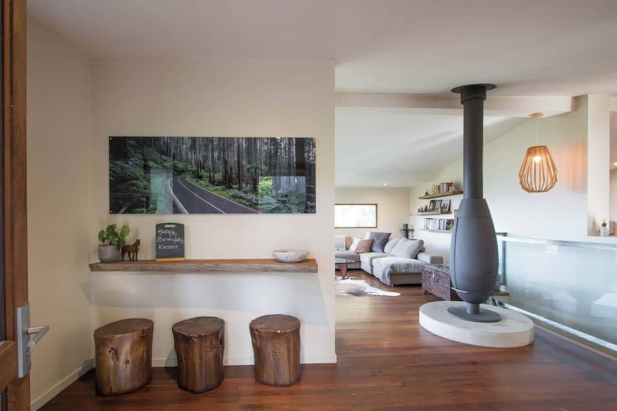 Uma sala de estar aconchegante com uma pintura grande, lareira, banquinhos de madeira e um espaço para sentar.
