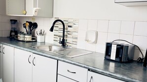 Eine moderne Küche mit weißen Schränken, einer Edelstahl-Spüle und einer Kaffeemaschine.