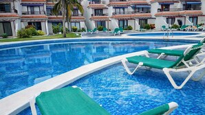 A swimming pool with green lounge chairs and a building with balconies in the background. - Beatifull apto lago azul 59 Los cancajos (Los Cancajos)