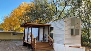 Une petite cabane avec une véranda en bois et des marches menant à une porte.