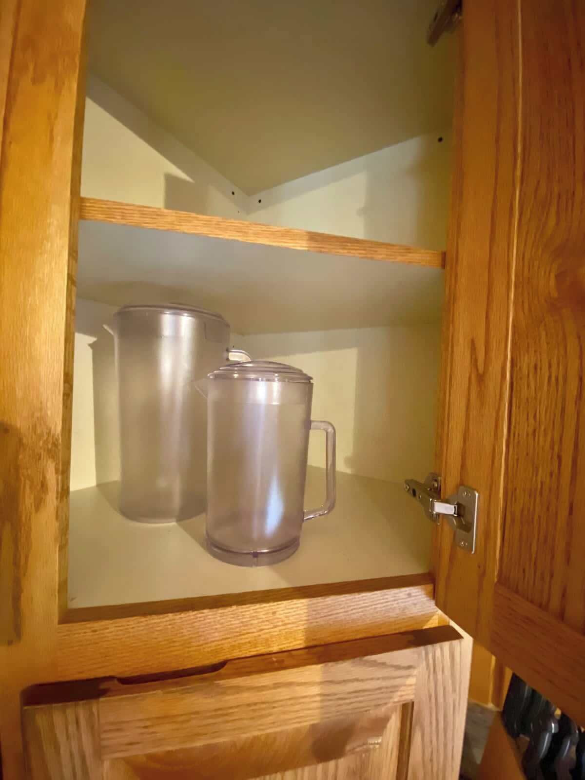 Ein Holzkabinent mit zwei Edelstahlbechern auf der Ablagefläche.