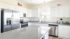 A modern kitchen with white cabinets, stainless steel appliances, and granite countertops. - High Noon - Hot Tub, Golf Cart, Dog Friendly! (Bolivar Peninsula)