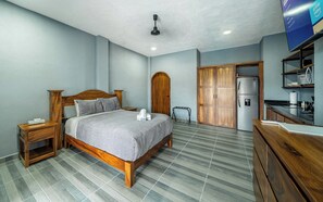 A bedroom with a bed, wooden wardrobe, and a kitchenette. - Modern Apartment in the Heart of Barra de Navid (Barra de Navidad)
