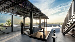 Una terraza en la azotea con zona de bar, paneles solares y vistas de la ciudad.
