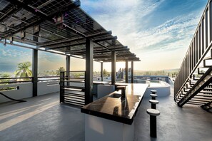 Eine Dachterrasse mit Barbereich, Solaranlagen und Blick auf die Stadtlandschaft.