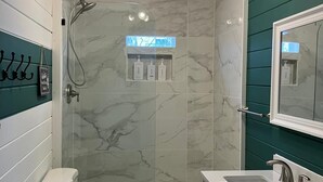 Une salle de bain moderne avec une douche à parois de verre, des toilettes blanches et un meuble-lavabo avec un miroir.