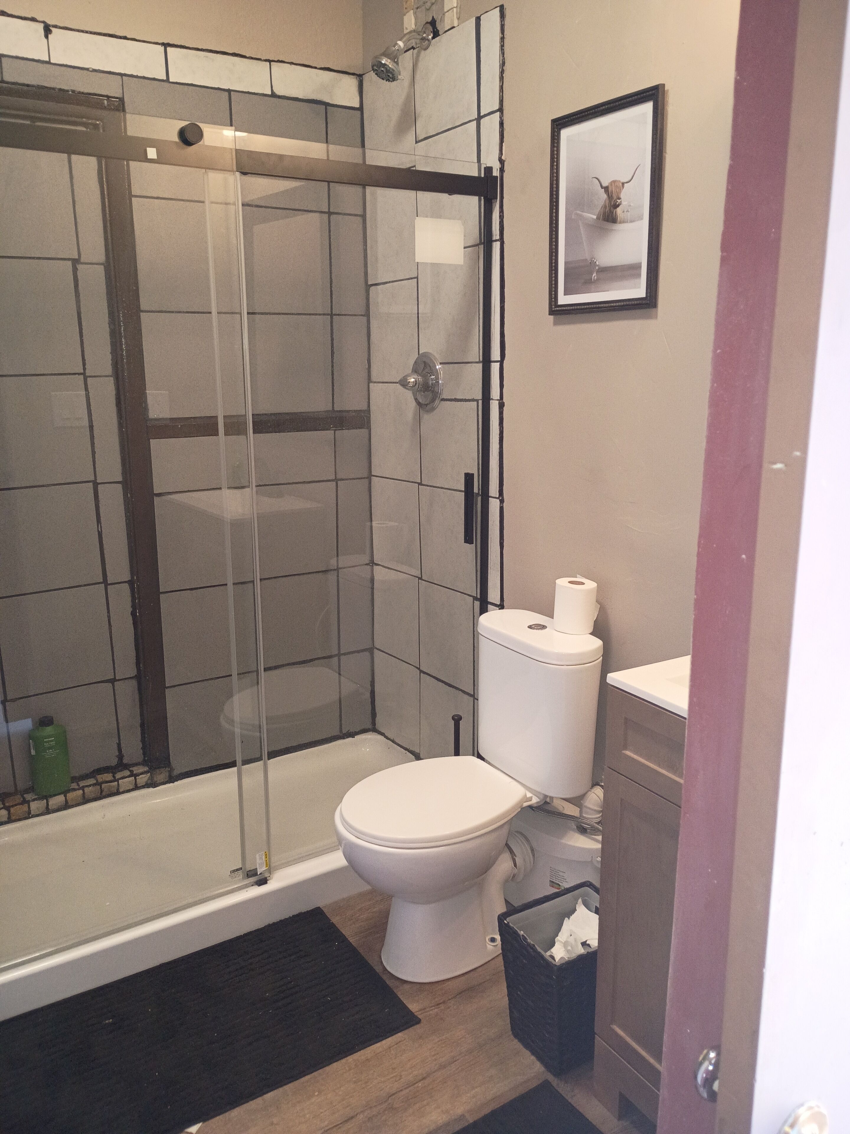 A bathroom with a glass-enclosed shower, a toilet, and a sink.
