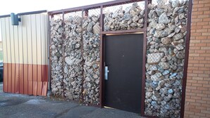 A building with a metal fence, a wooden door, and a gravel ground. - Creative Industrial Retreat with Decks, Games, Hot Tub & Spray Paint Trailer (Albuquerque)