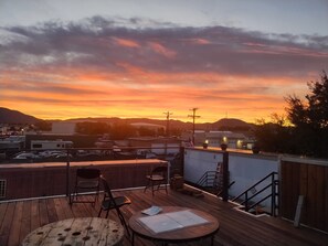 A rooftop patio with a view of a sunset over a cityscape. - Creative Industrial Retreat with Decks, Games, Hot Tub & Spray Paint Trailer (Albuquerque)