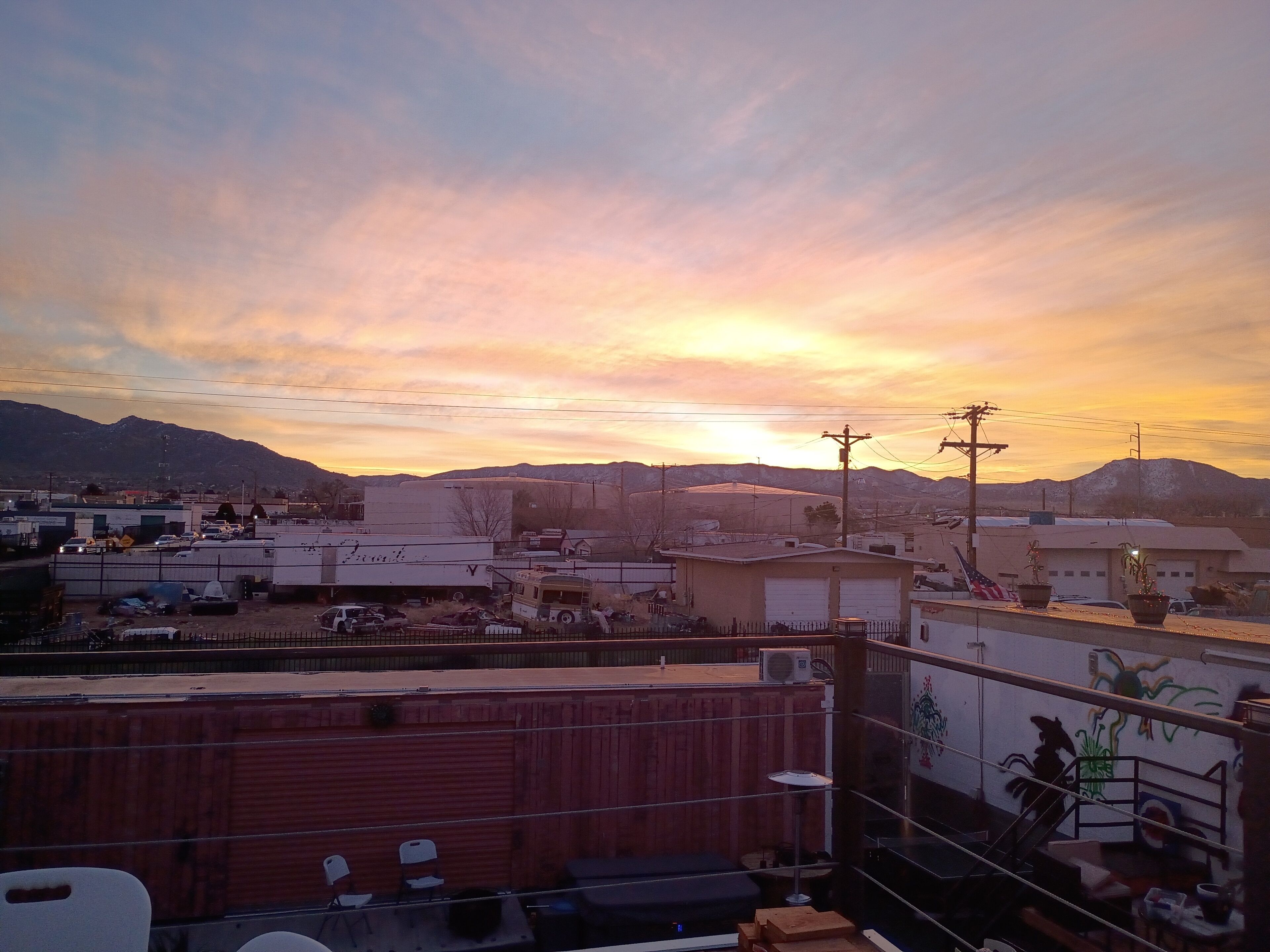 A view of a cityscape with mountains in the background during sunset.