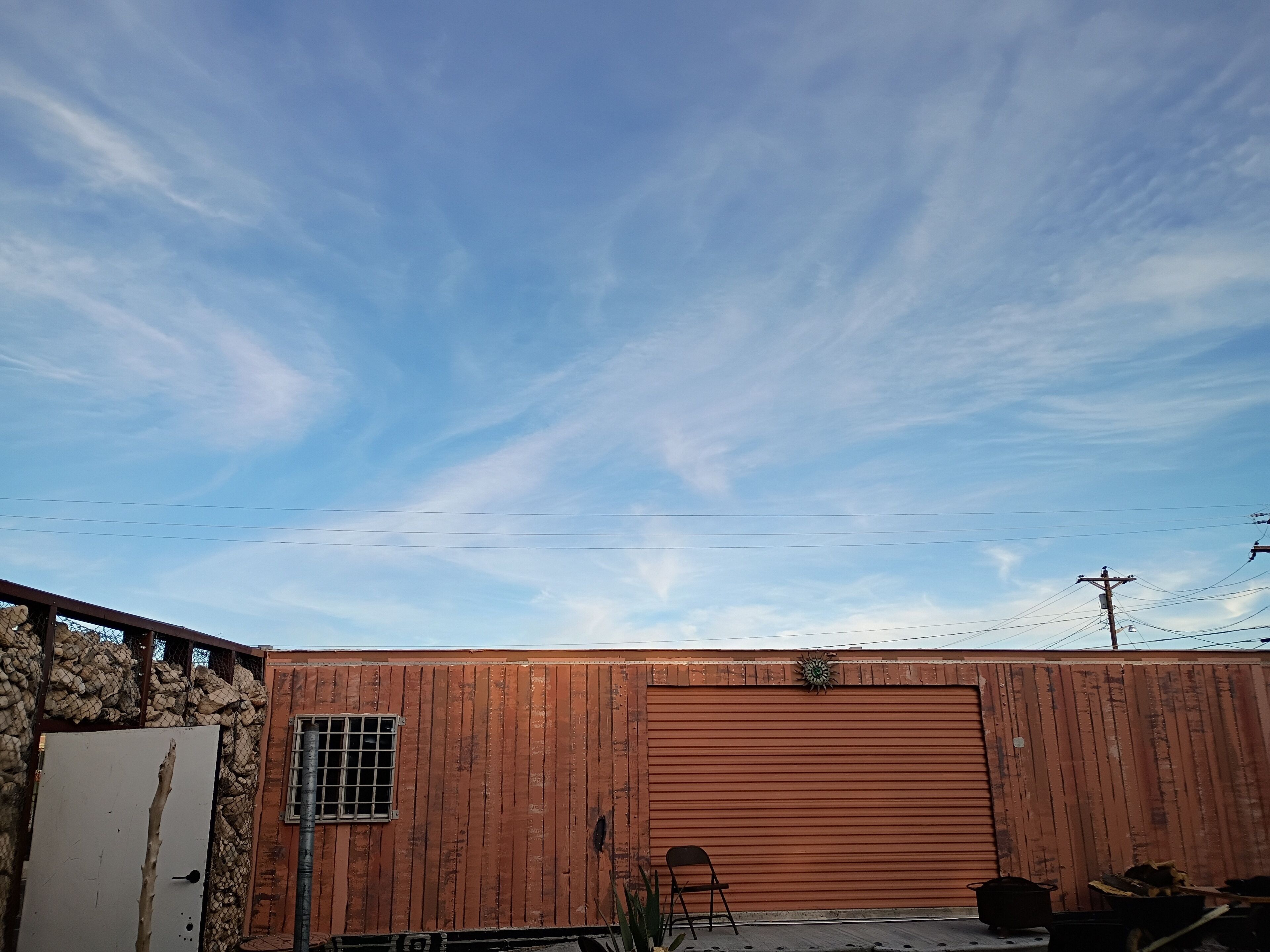 A wooden building with a large garage door, a small window, and a metal gate.