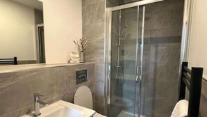 A modern bathroom with a glass-enclosed shower, a standalone bathtub, and a toilet. - Chic York Apartment - Free Parking & Gym Access (York)