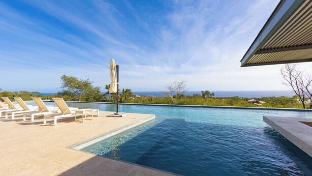 A swimming pool with lounge chairs and a view of the ocean. - Brisa Del Sol - Cabo Costa (Cabo San Lucas)