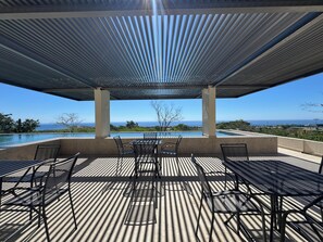 A covered outdoor area with a pool, tables, and chairs, overlooking a scenic view. - Brisa Del Sol - Cabo Costa (Cabo San Lucas)