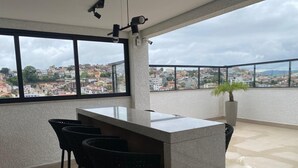 Ein Balkon mit Bar, Stühlen und einem Blumentopf.