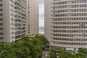 Ein Hochhaus mit mehreren Balkonen, Blick auf den Ozean und umliegender Bepflanzung.