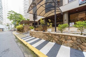 Ein Hotel mit steinverkleideter Fassade, einer überdachten Terrasse und einer Fußgängerüberweg.