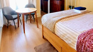 Una habitación de hotel con una cama, un escritorio, una silla, un televisor y una pequeña kitchenette.