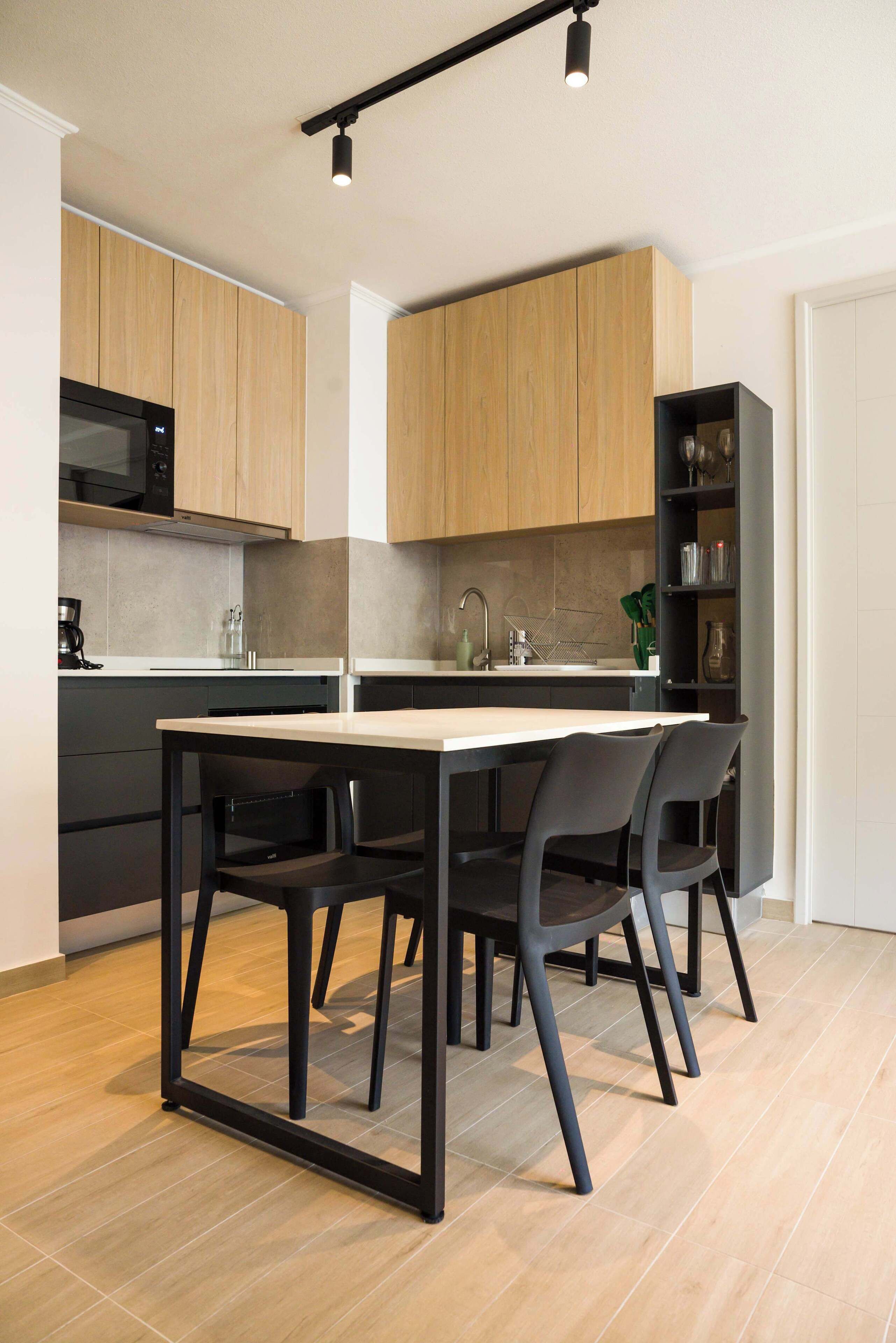 A modern kitchen with wooden cabinets, a black countertop, and a dining area with a table and chairs.