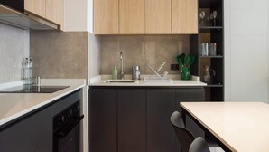 A modern kitchen with dark cabinets, a white countertop, and a built-in oven. - Best of Providencia Modern 2BR Steps from Metro (Providencia)