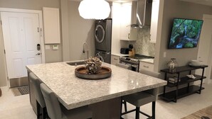 Una cucina moderna con una grande isola, elettrodomestici in acciaio inossidabile e una televisione a schermo piatto montata a parete.