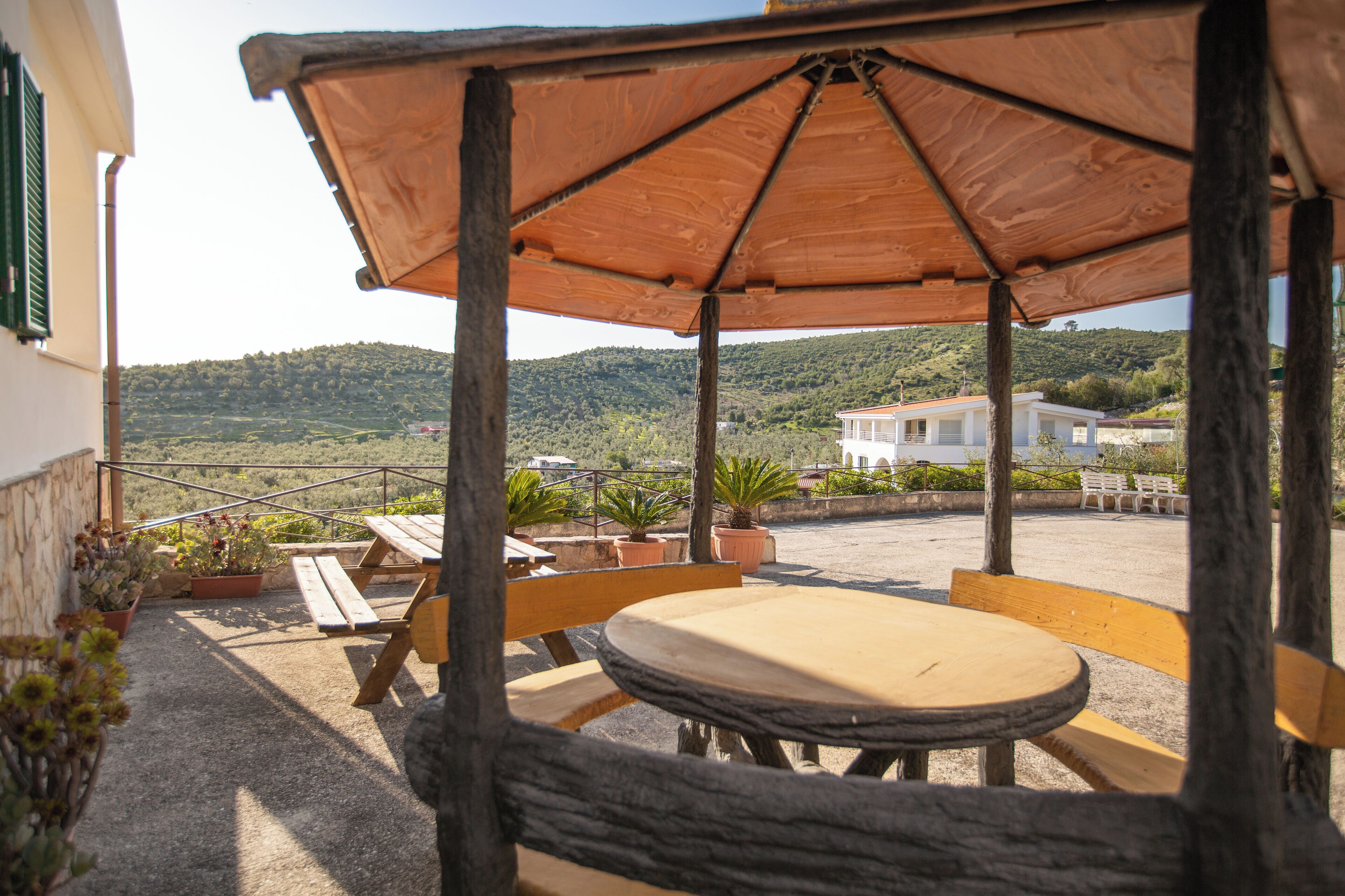 Un patio al aire libre con mobiliario de madera, una mesa y un banco.